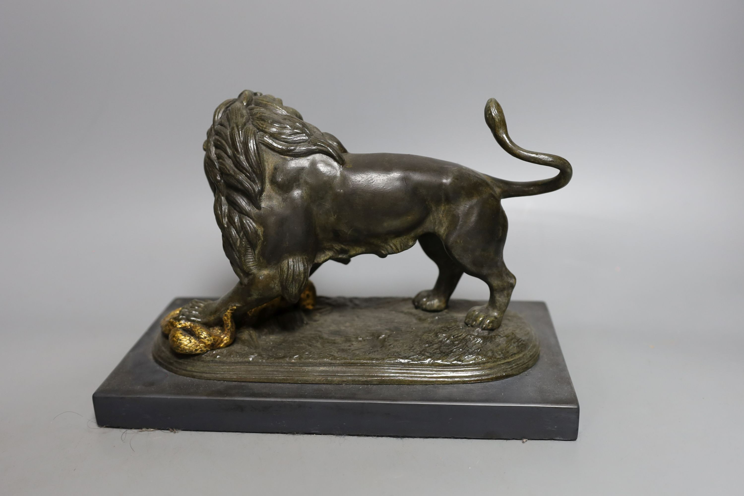 A patinated spelter figure of a lion slaying a serpent on mounted base - 24cm long